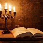 Open Holy Bible and candle on a old oak wooden table. Beautiful