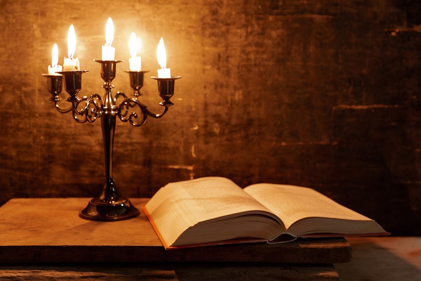 Open Holy Bible and candle on a old oak wooden table. Beautiful